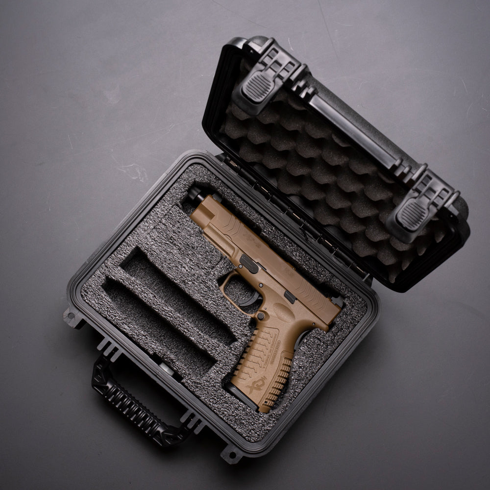 Alt text: "Open rugged case with a pre-cut foam insert showcasing a single slot containing a tan handgun and two additional slots for magazines, designed for secure storage and protection."