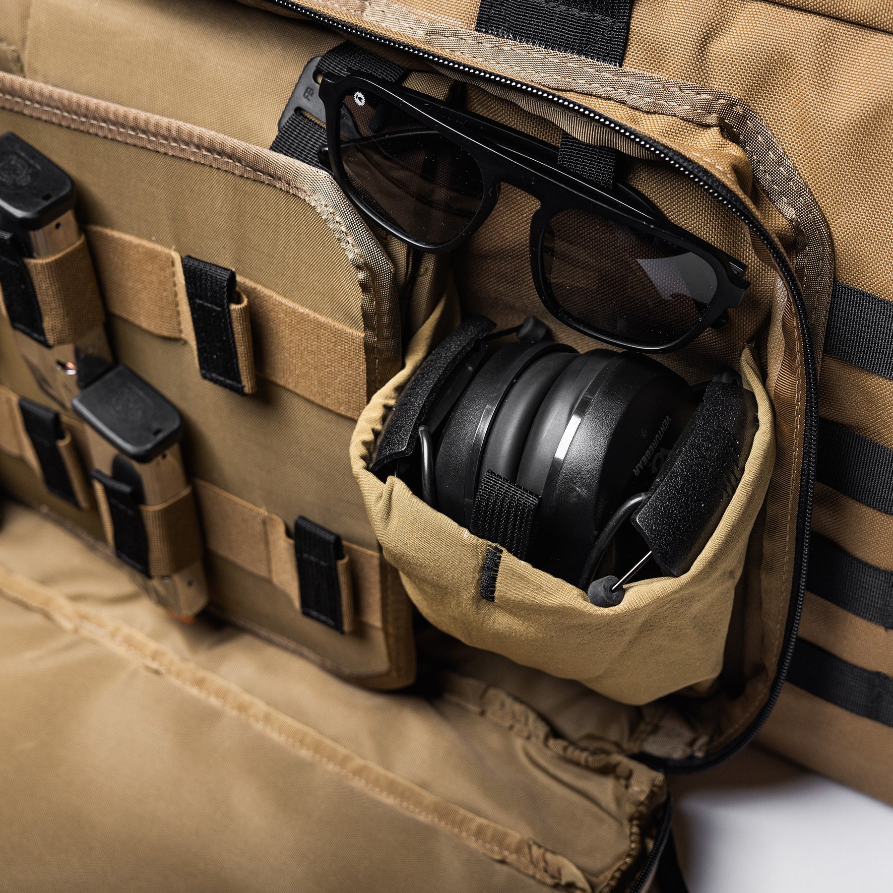 Close-up of a tan Lone Star 36" rifle bag with sunglasses, ear protection, and small gear compartments inside.
