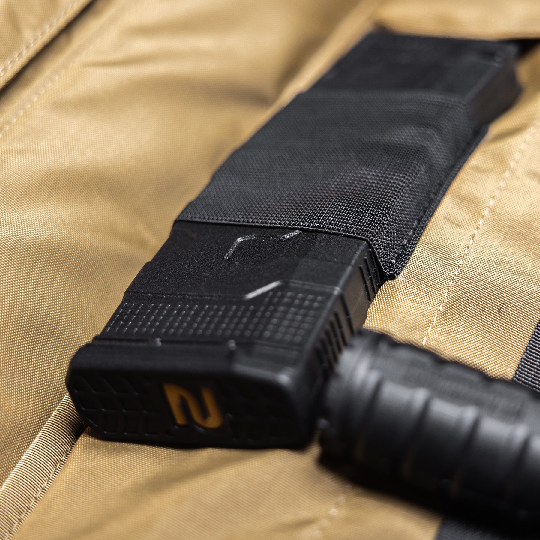 Close-up of a black rifle scope mounted on a tan Lone Star 36" rifle bag, showing durable fabric and secure attachment.