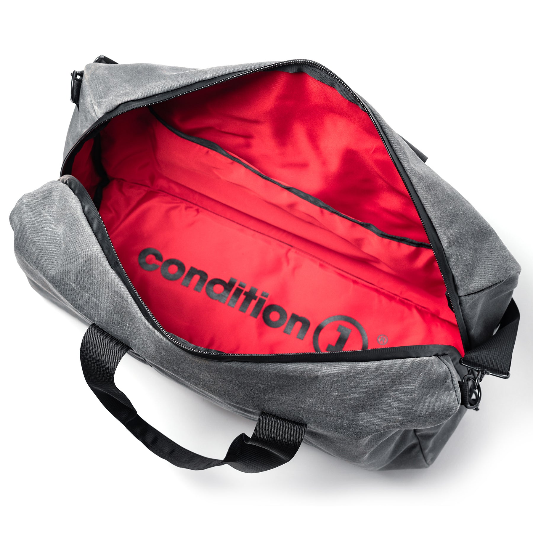 Open gray waxed canvas duffle bag with red interior lining and black "condition 1" logo, showing spacious storage.
