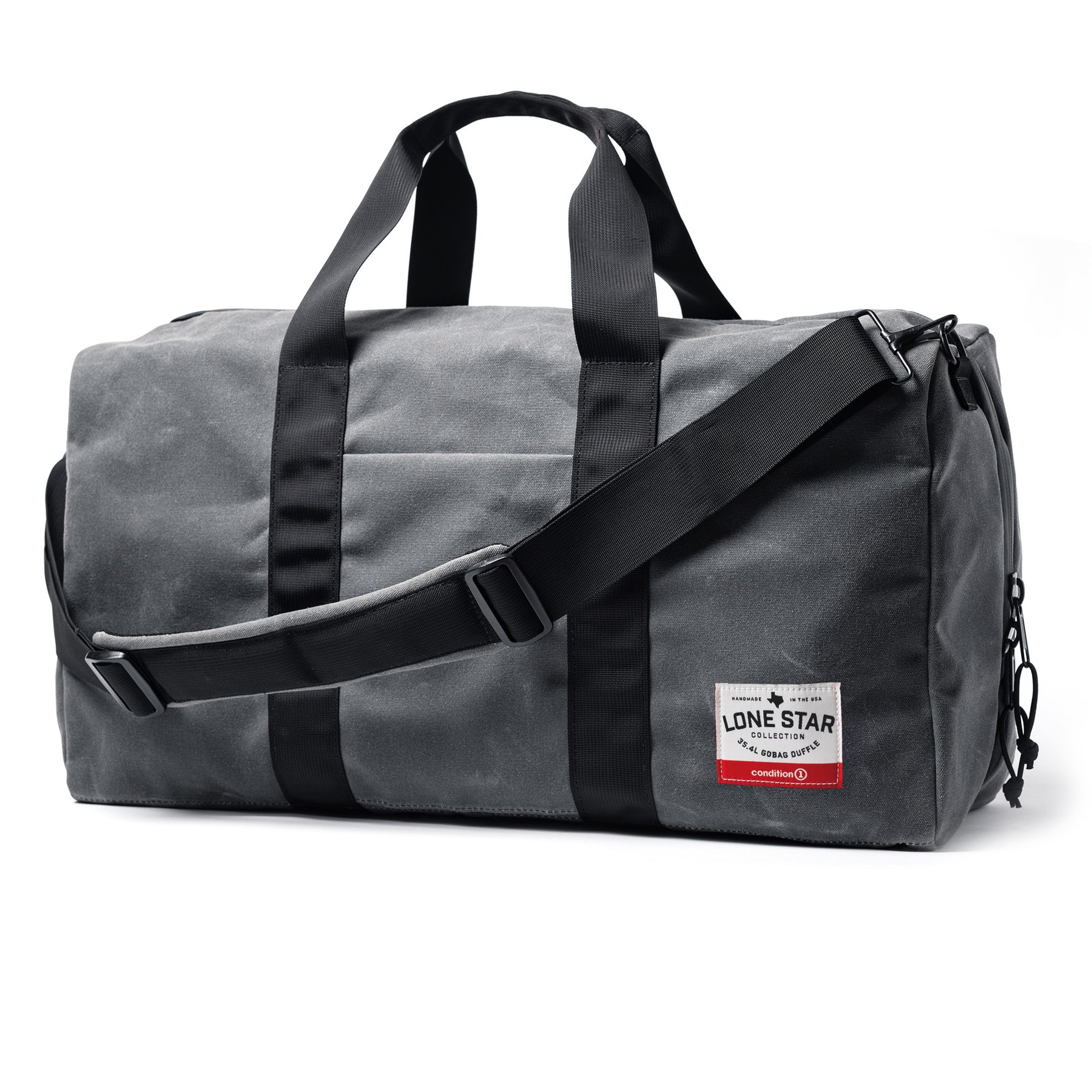 Gray waxed canvas duffle bag with black straps, handles, and adjustable shoulder strap, featuring a red and white label.
