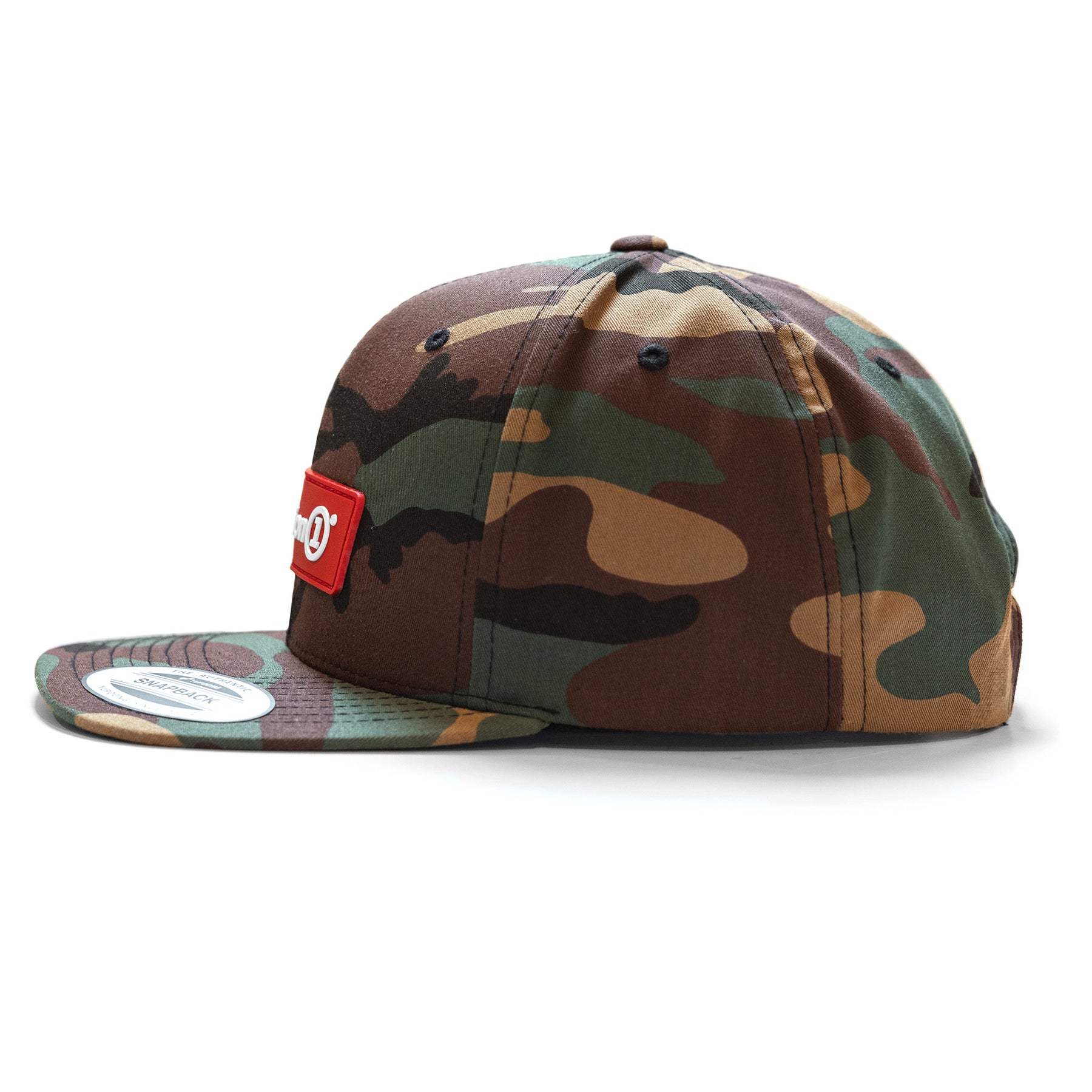 Camouflage snapback cap with a red logo patch on the front, adjustable snap closure, and black eyelets for ventilation.