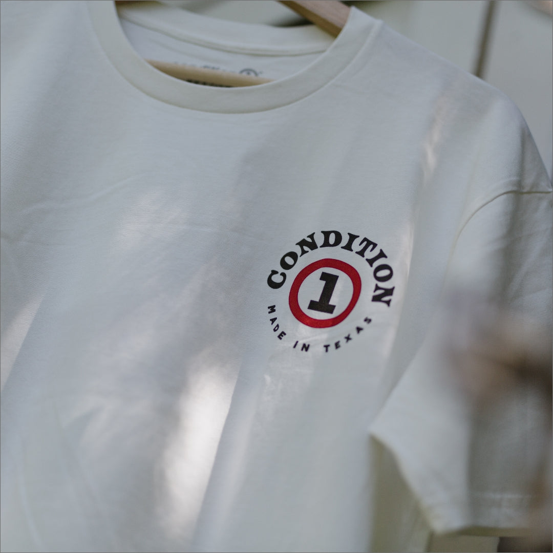 White "Like A Tank" T-shirt with a circular logo featuring the number 1 and "Made in Texas" text.