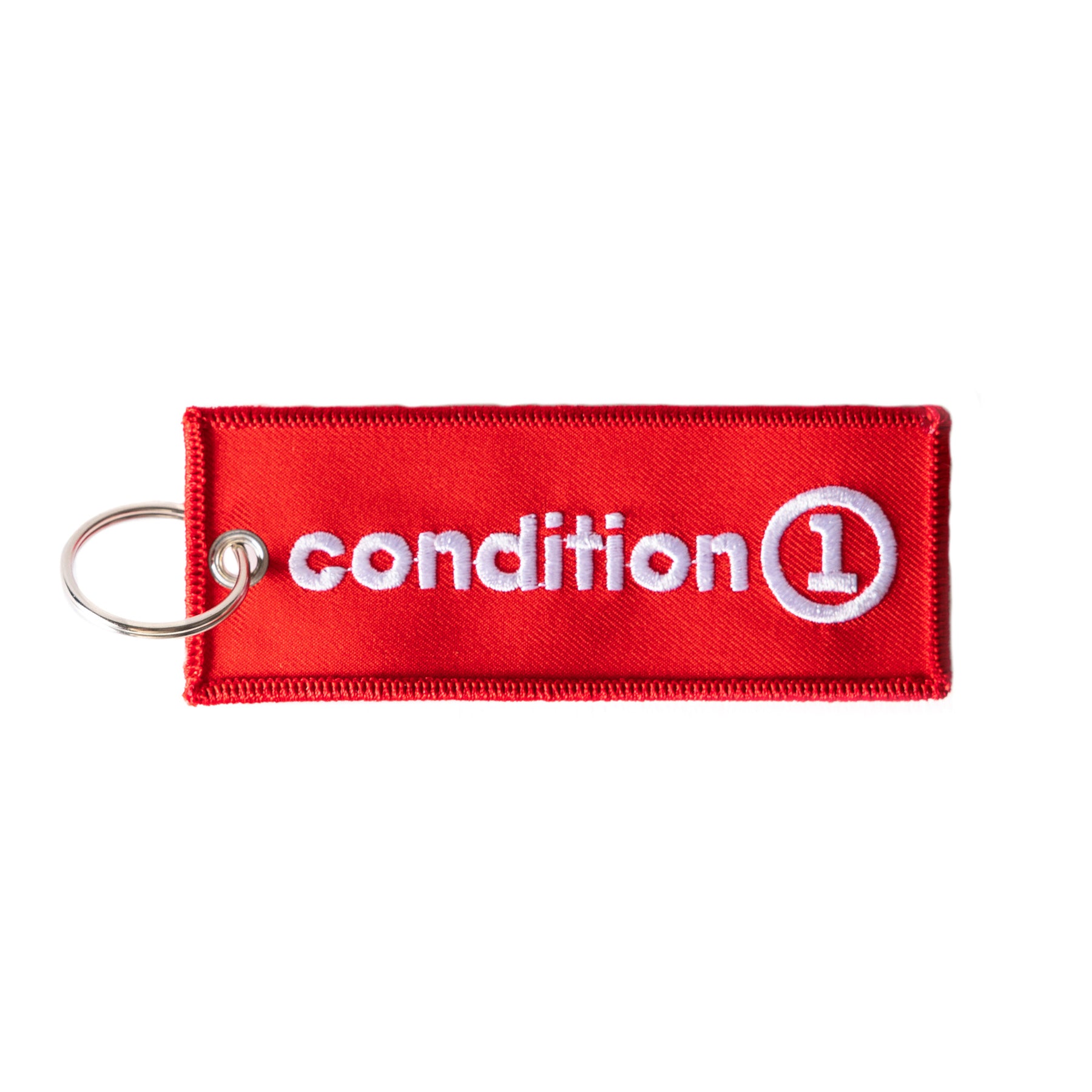 Red fabric keychain with white embroidered "Condition 1" logo and a metal keyring attachment.