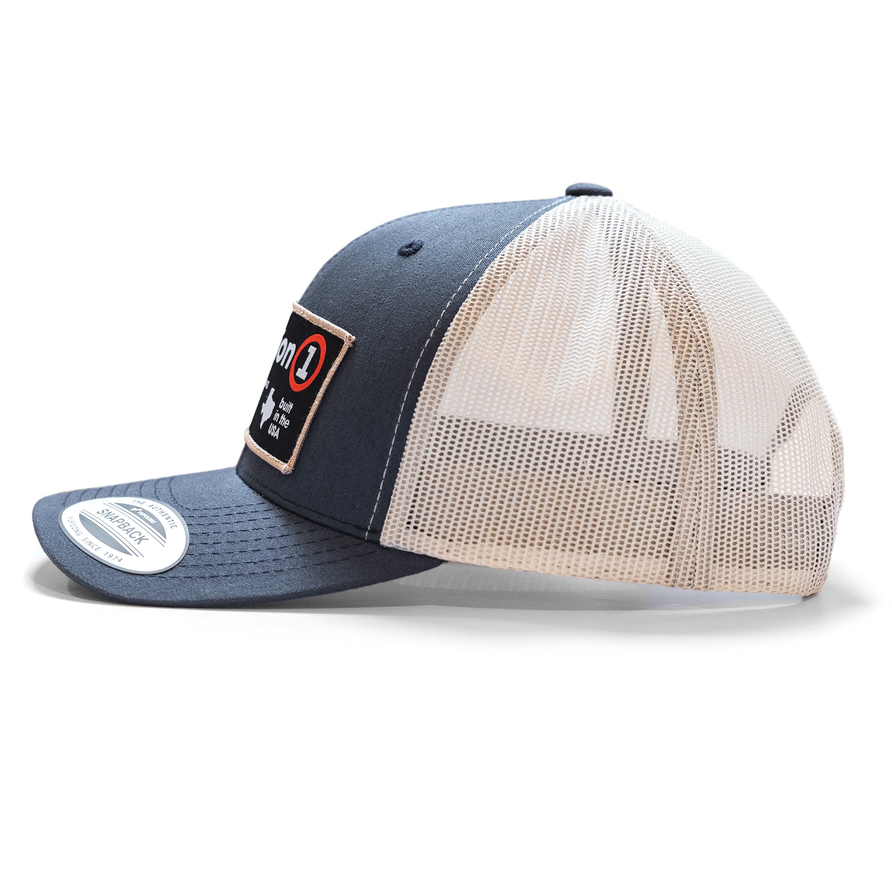 The Label snapback hat with a navy front, beige mesh back, and a patch reading "on 1" on the front panel.