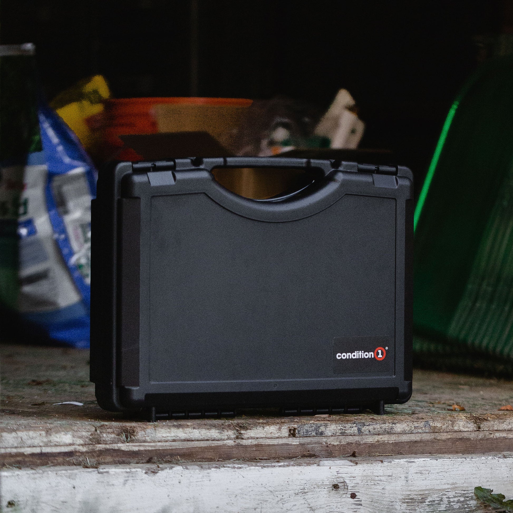Alt text: "A 17-inch Economy Case #1764 by Condition 1, displayed on a wooden surface in a dimly lit garage setting, showing its durable, black exterior design."