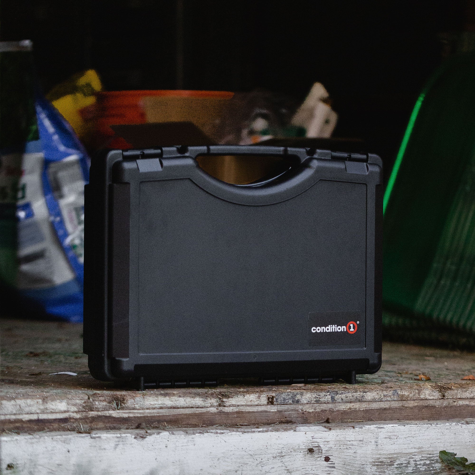Alt text: "A 17-inch Economy Case #1764 by Condition 1, displayed on a wooden surface in a dimly lit garage setting, showing its durable, black exterior design."