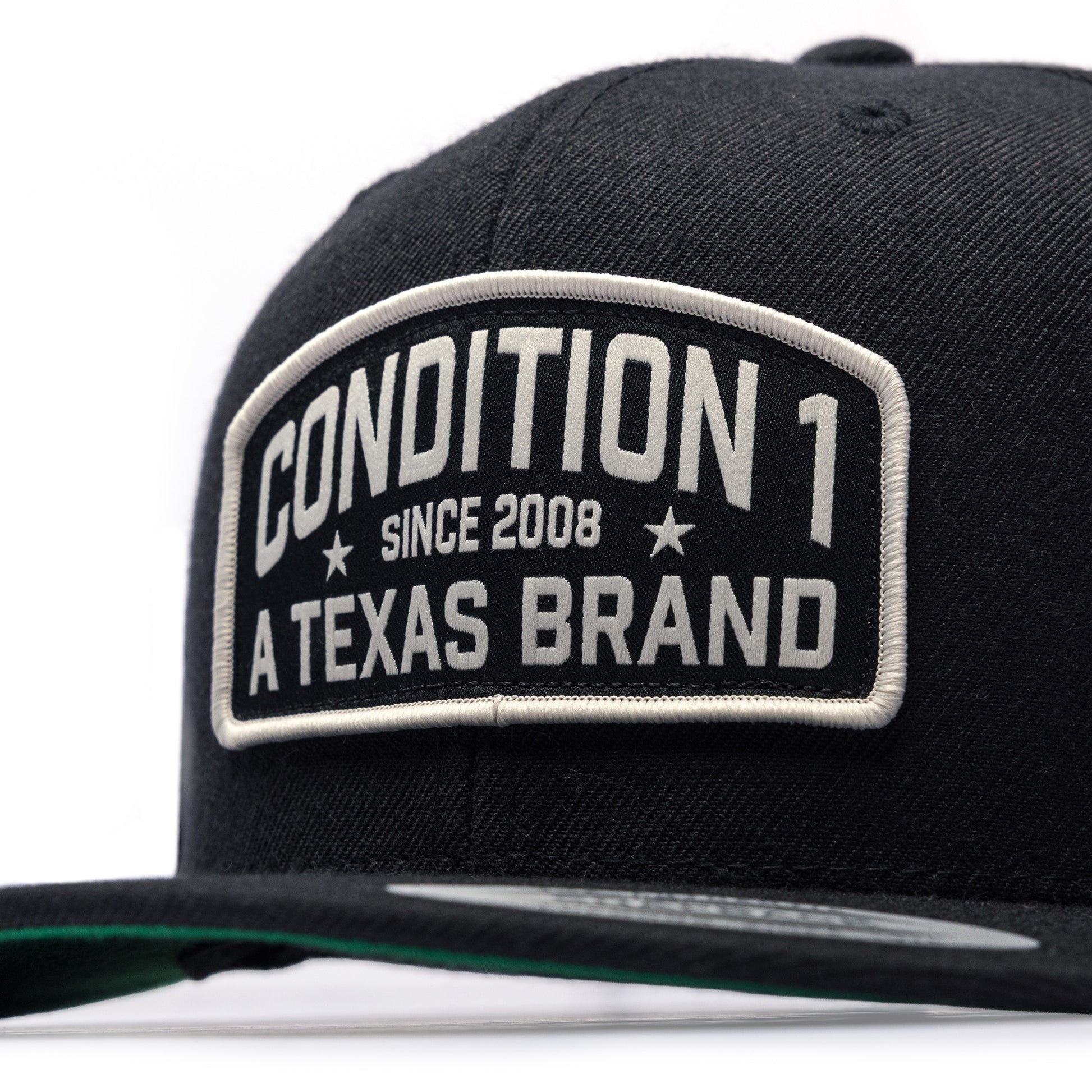 Black snapback cap featuring a prominent patch with "Condition 1 Since 2008 A Texas Brand" in bold lettering.
