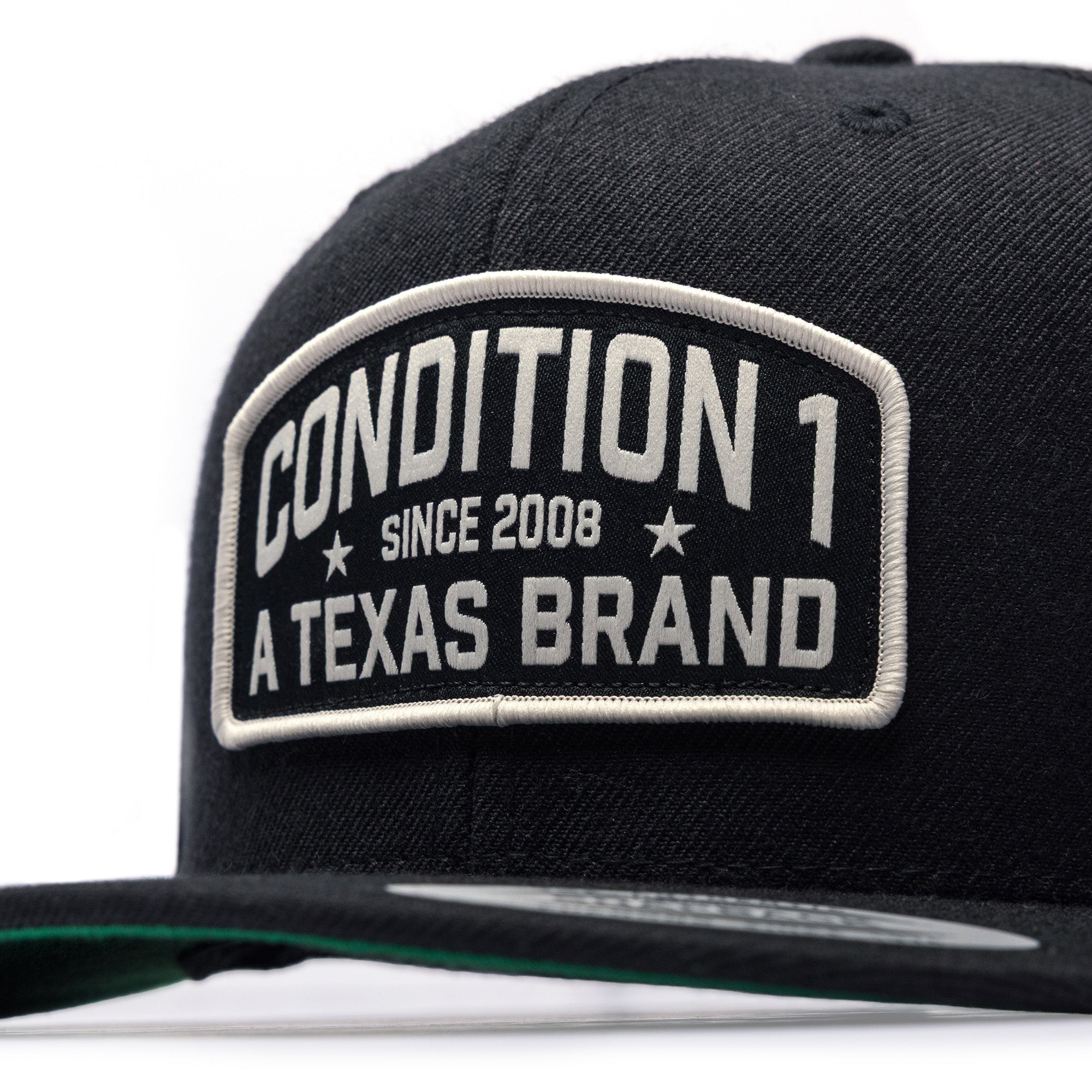 Black snapback cap featuring a prominent patch with "Condition 1 Since 2008 A Texas Brand" in bold lettering.