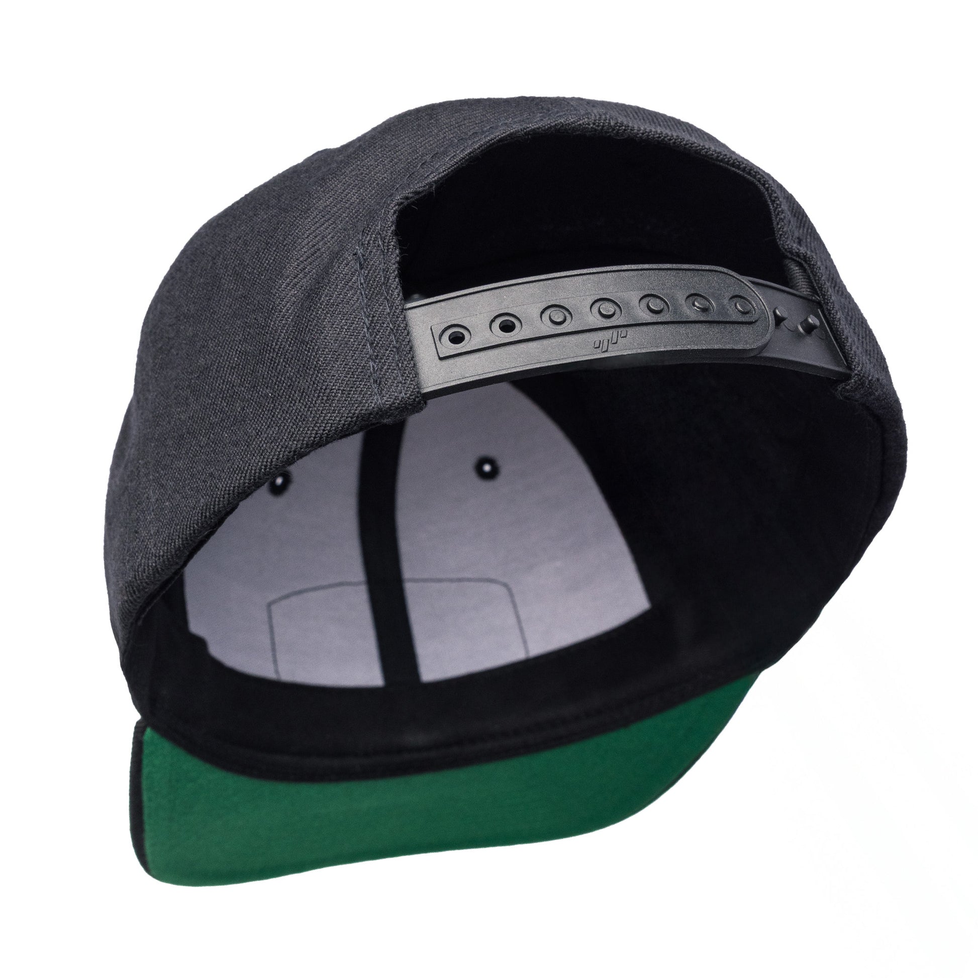 Texas Brand snapback cap featuring a black exterior and green visor, showcasing the adjustable strap inside.