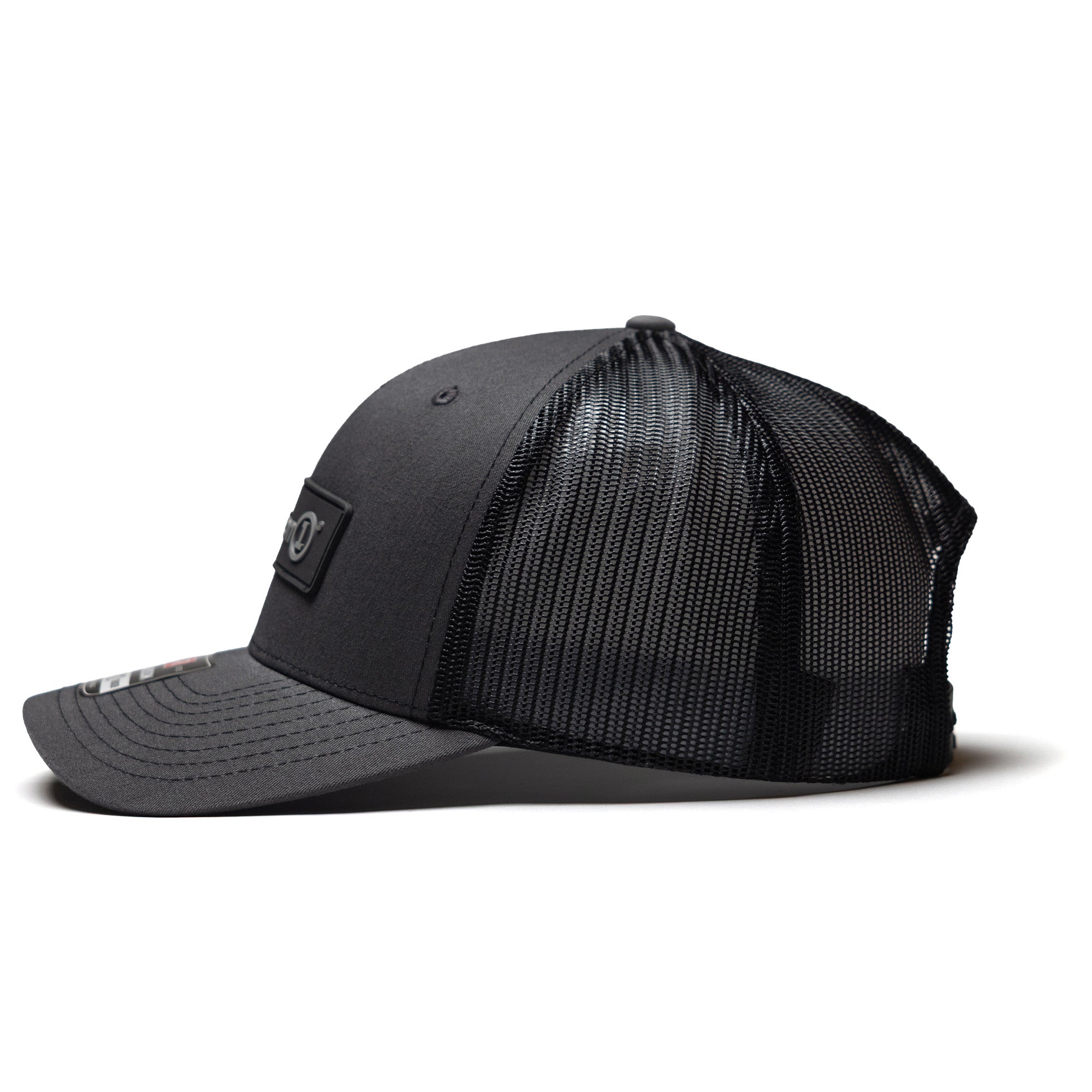 Black snapback cap with a curved brim and mesh back panel, featuring a Defender logo patch on the front.