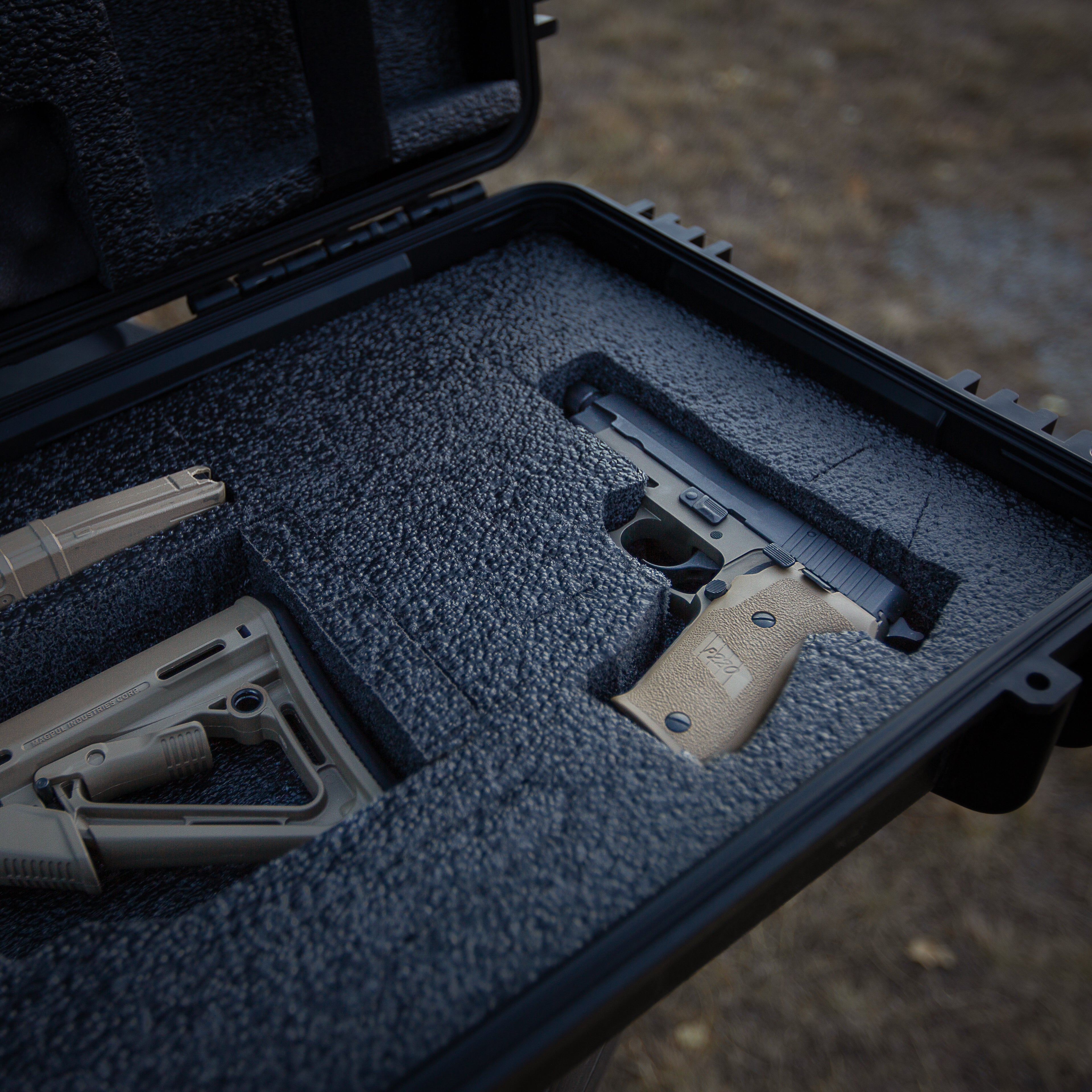 Black 55-inch gun case with foam interior, holding a handgun and accessories, designed for firearm storage and transport.